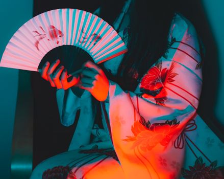 一名身着传统和服的女子手持扇子，在鲜艳的红蓝灯光映照下