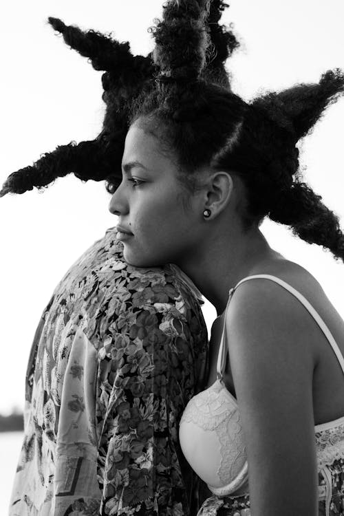 Black and white side view of peaceful African American couple standing close to each other and hugging