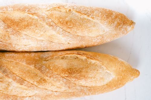 Free Top view of two golden brown baguettes on a white marble surface, showcasing their crusty texture. Stock Photo