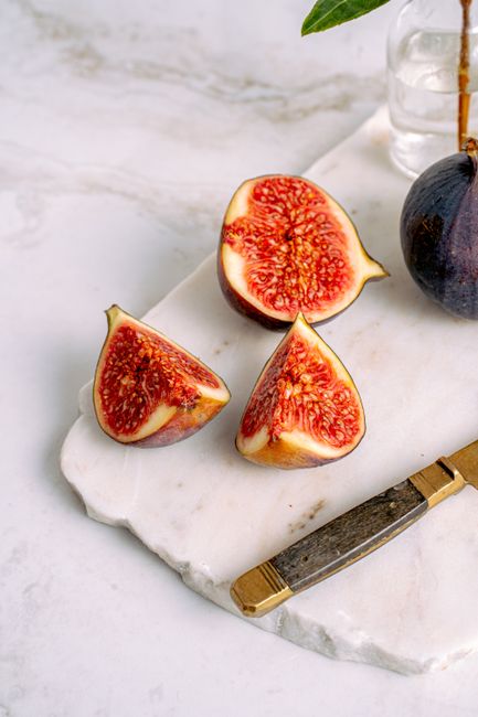Close-up of sliced figs on a marble board with a knife, showcasing their rich texture.