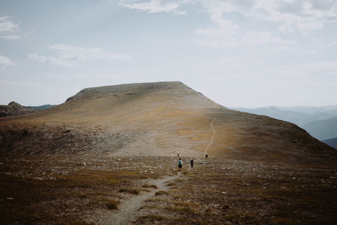 Distant travelers walking on hillside