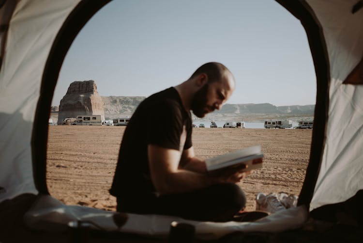 Man Reading Book In Tent