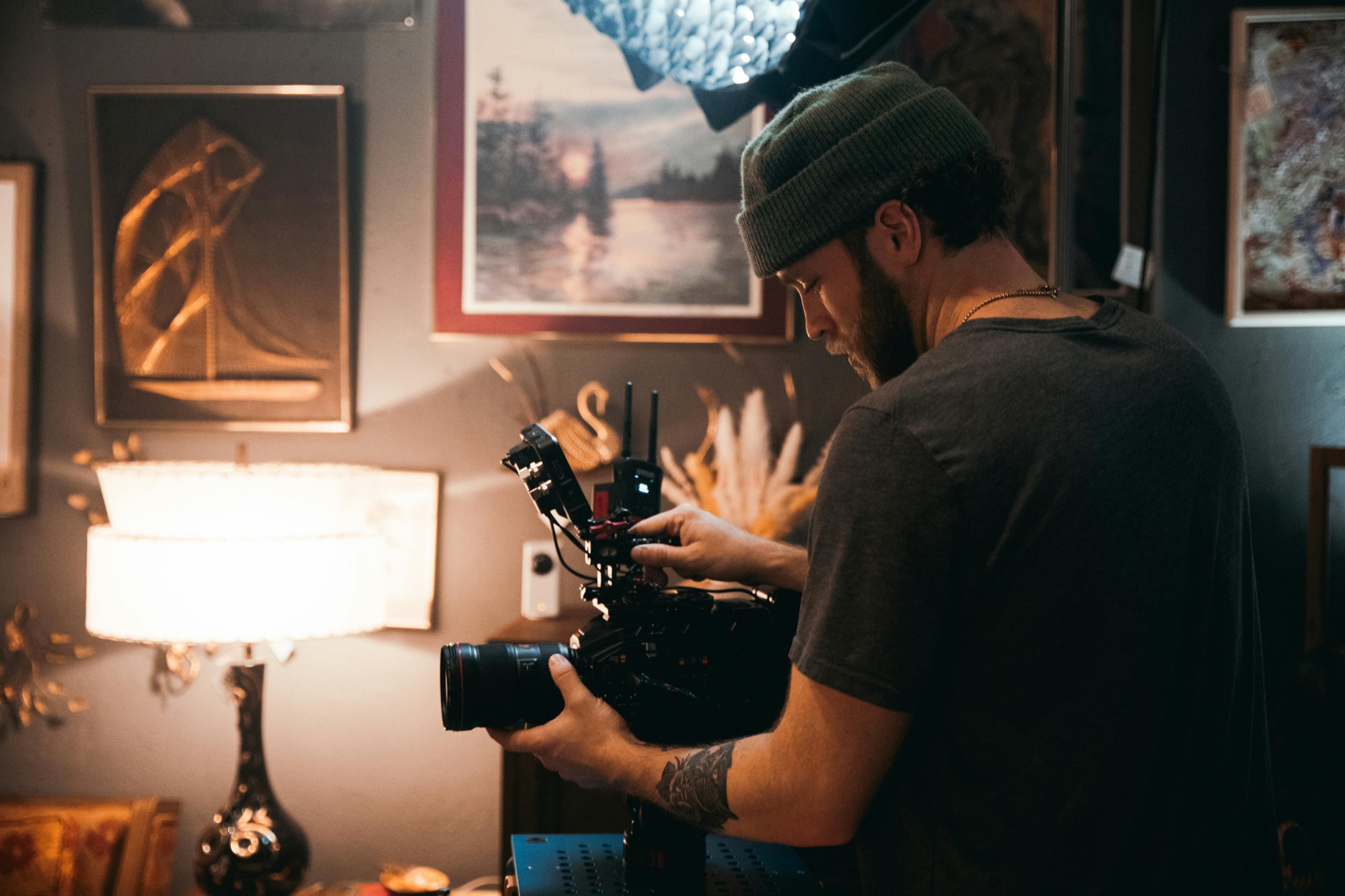 Professional videographer operating a camera in a cozy, art-filled studio.
