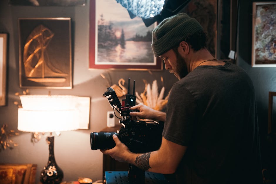 Professional videographer operating a camera in a cozy, art-filled studio.