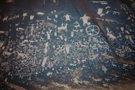 Newspaper rock with ancient symbols and petroglyphs with white paint on shabby stone blue wall with uneven surface in national park