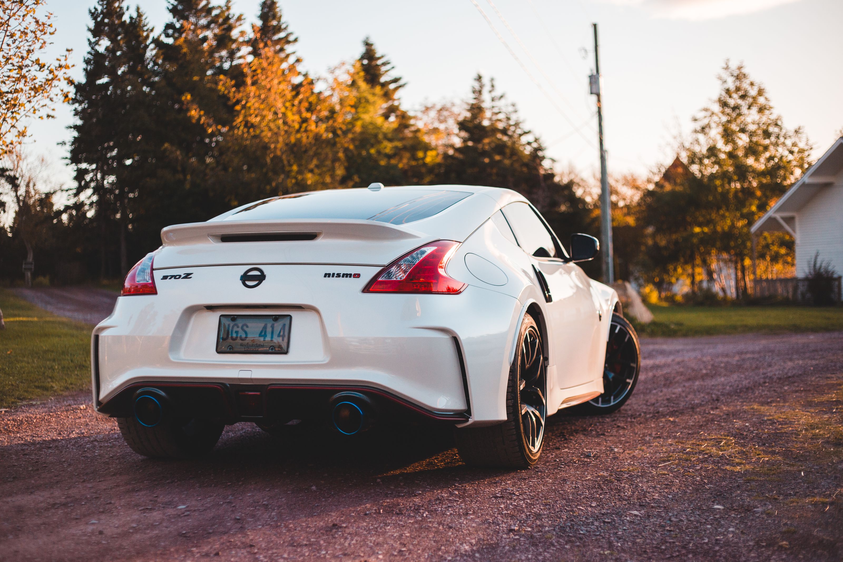 Luxury white sports car with exhaust tubes and tuned details riding on rural road near forest in countryside