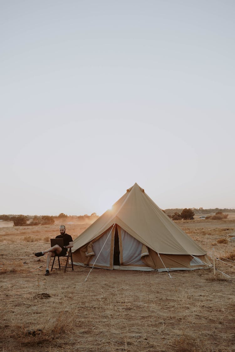 Man Working With Laptop Near Tent