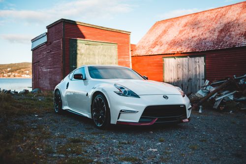 Free Luxury car parked near small brick buildings located on shore of river in sunny day Stock Photo