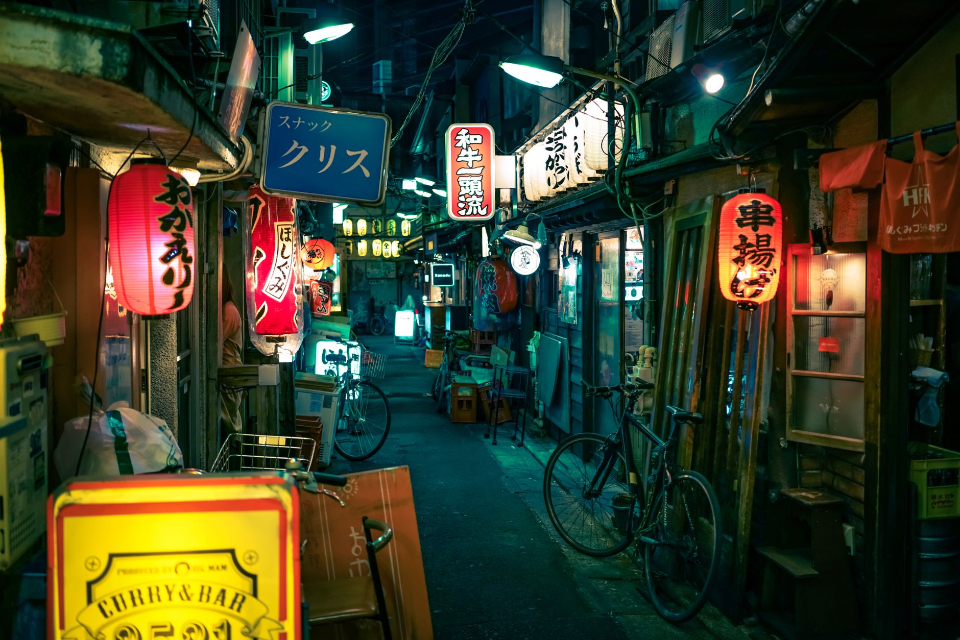 Night scene of a bustling Tokyo alley with colorful lanterns and signs.