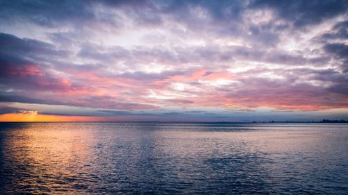 Free A breathtaking view of the ocean at sunset with colorful clouds and reflections on the water. Stock Photo