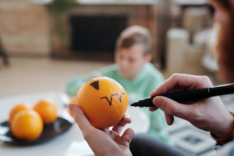 Man Making A Drawing On An Orange Fruit