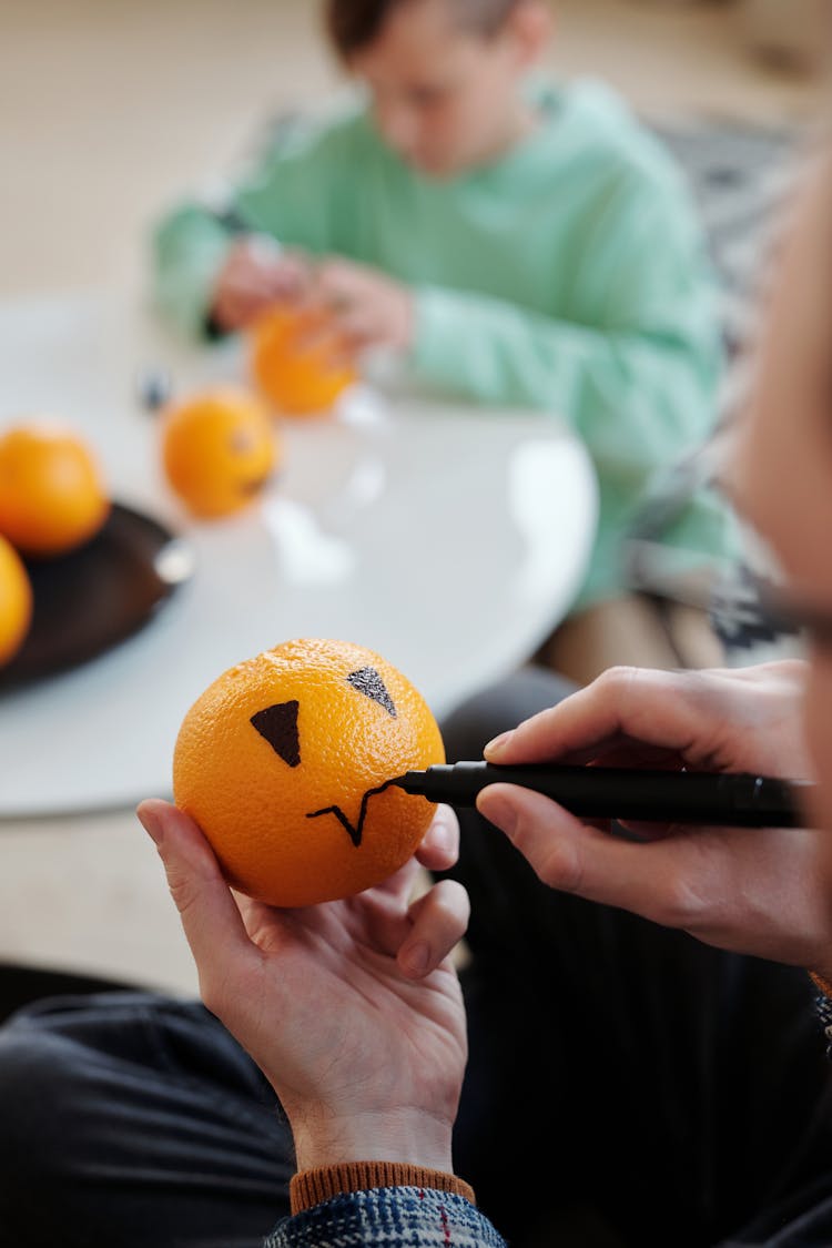 Man Making A Drawing On An Orange Fruit