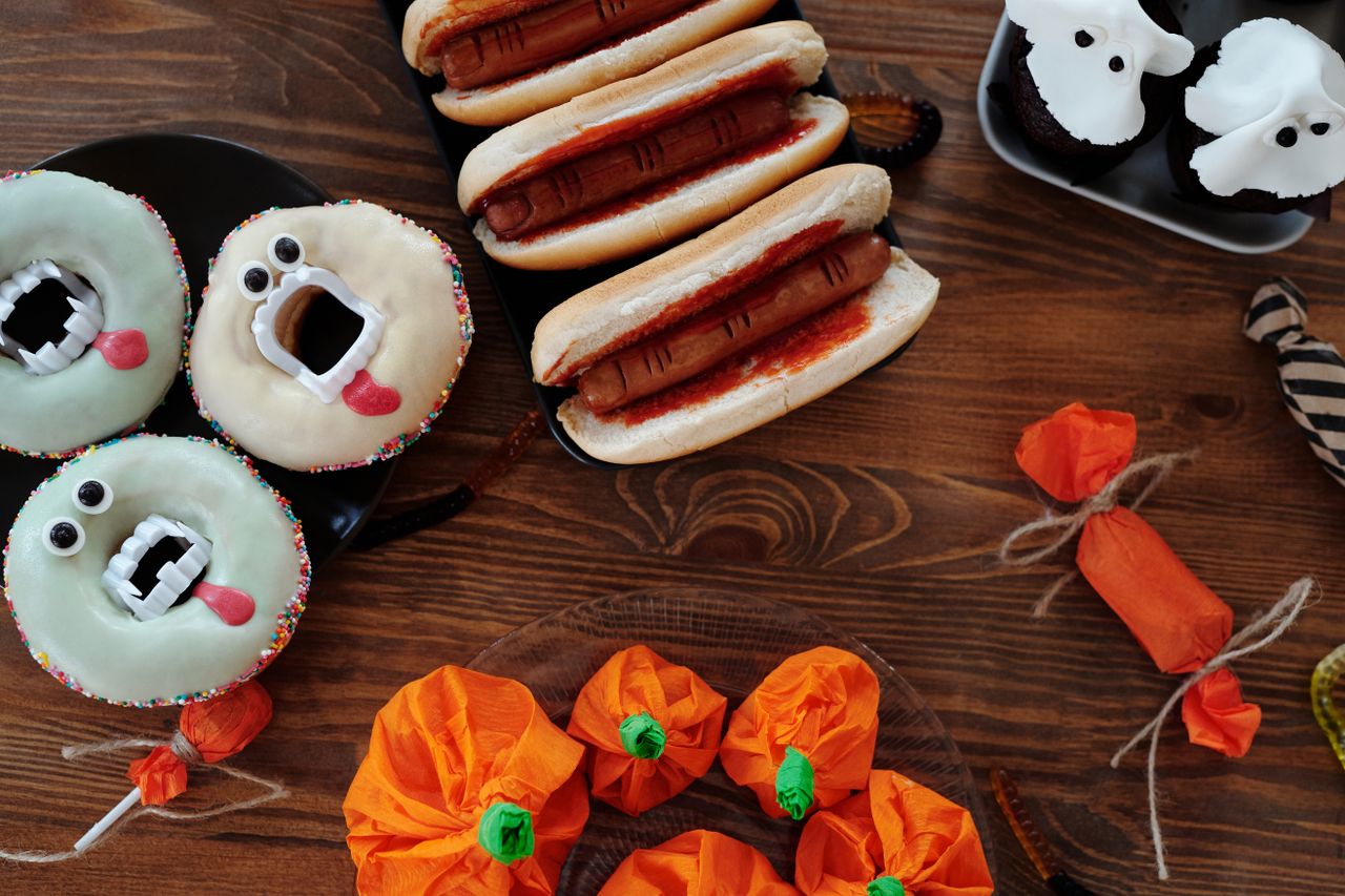 Halloween treats including donuts and hot dogs on a wooden table
