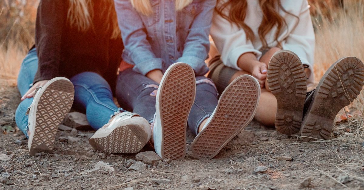 Three women relaxing outdoors in summer, focused on footwear and leisure.
