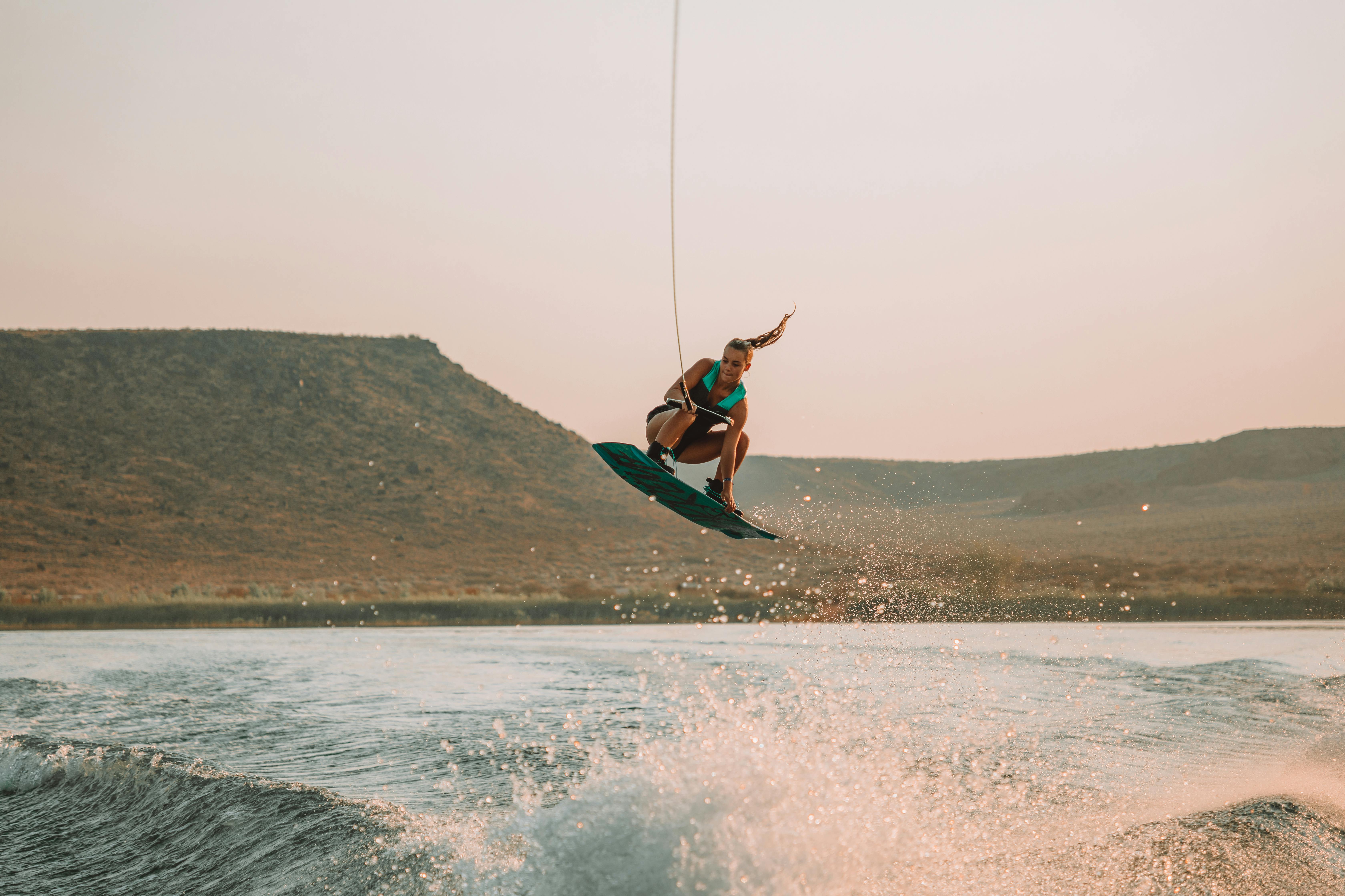 A woman enjoys an action-packed wakeboarding session on a sunny lake day.
