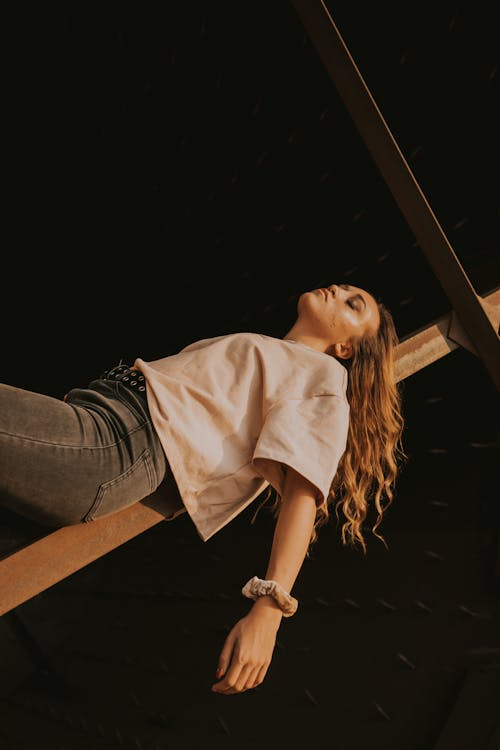 A Woman in White Shirt Lying on Wood Plank