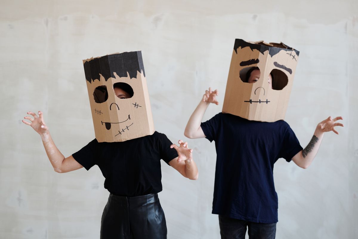 Dos personas con máscaras caseras hechas con cajas de cartón