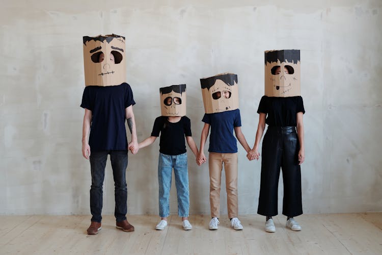 A Family Wearing Diy Cardboard Box Mask While Holding Each Other's Hands