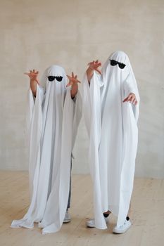万圣节期间，两个穿着时尚幽灵服装、戴着太阳镜的人在室内度过