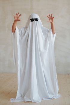 一个戴着太阳镜、穿着创意幽灵服装的人在室内开玩笑地摆姿势