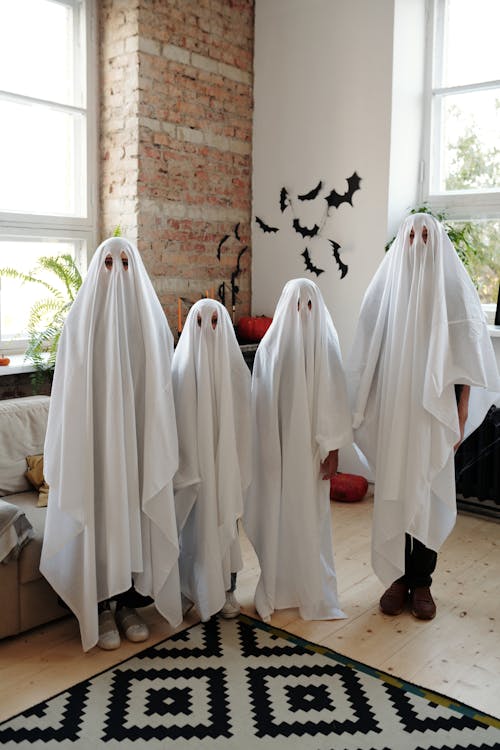 Uma Família Vestindo Uma Fantasia Branca De Halloween Enquanto Está De Pé  Na Sala · Foto profissional gratuita