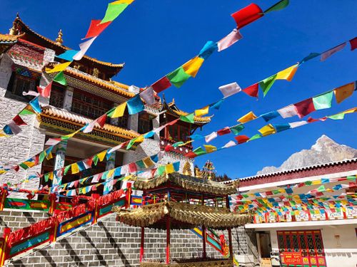 Free Vibrant Tibetan monastery with prayer flags under a clear blue sky in Sichuan, China. Stock Photo