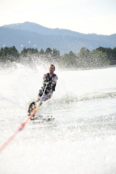A thrill-seeker enjoys waterskiing surrounded by mountains and splashing water.