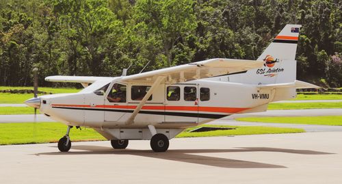 Free A small aircraft parked on a tarmac surrounded by lush greenery under daylight. Stock Photo