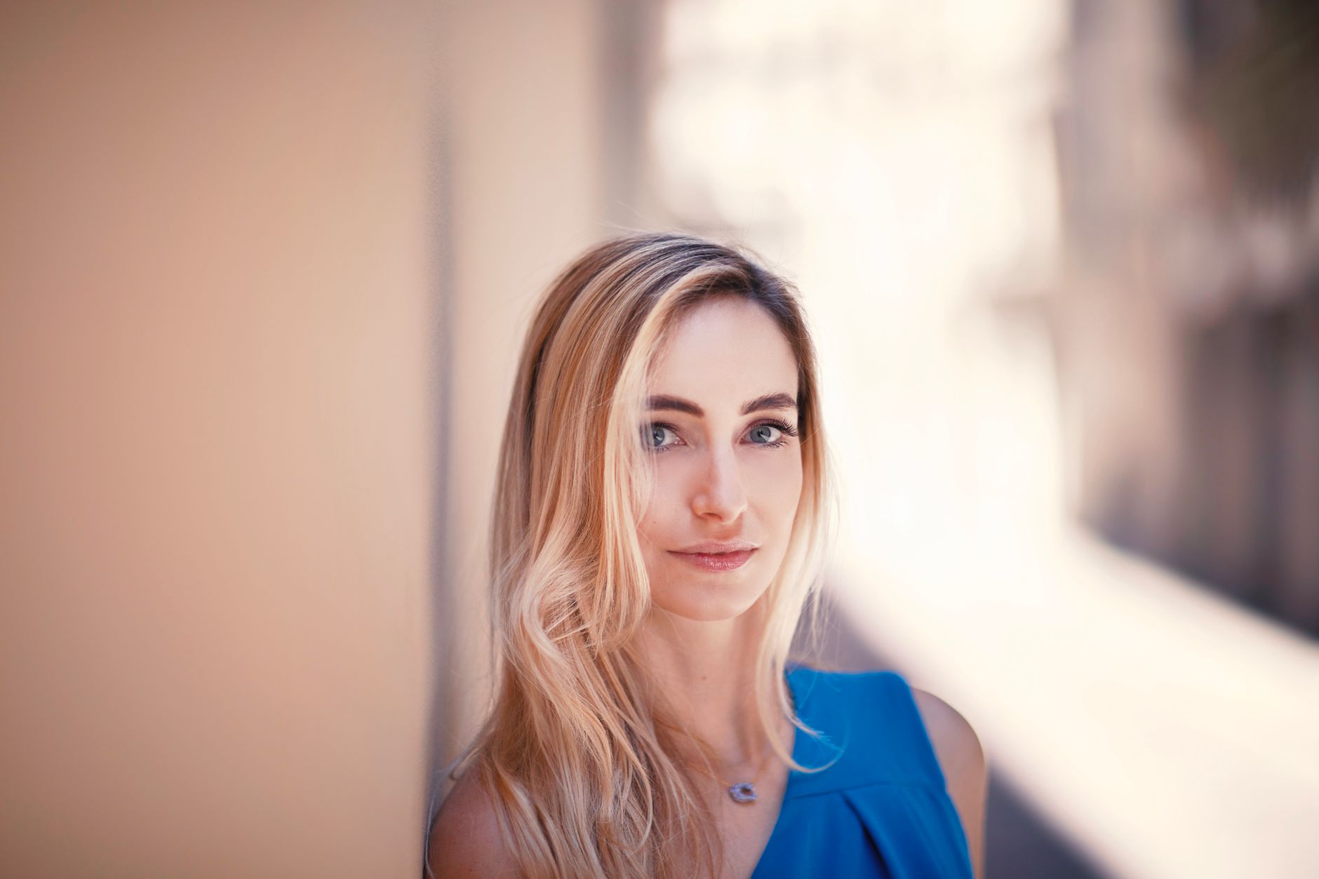 Portrait of a blond woman in a blue dress with a soft background.