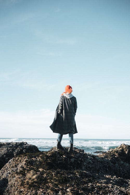 Faceless woman on rocky coast near sea