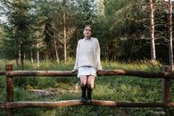Woman in White Sweater Sitting on Brown Wooden Fence