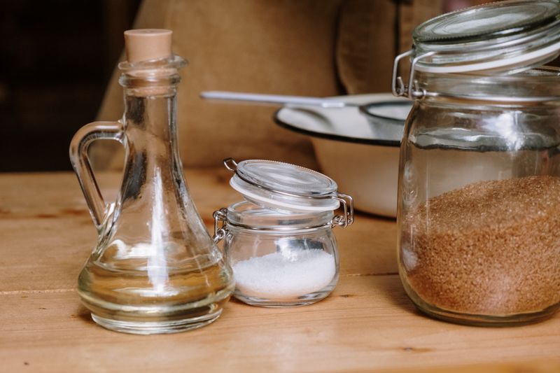 Assorted kitchen ingredients in glass jars on a wooden countertop.