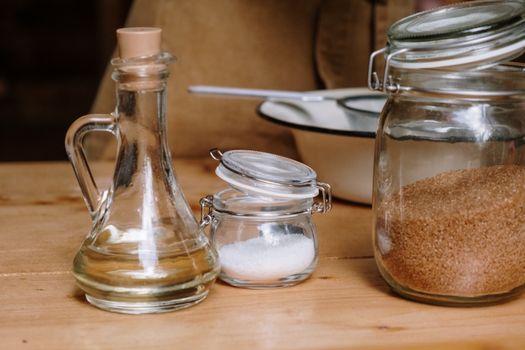 Assorted kitchen ingredients in glass jars on a wooden countertop.