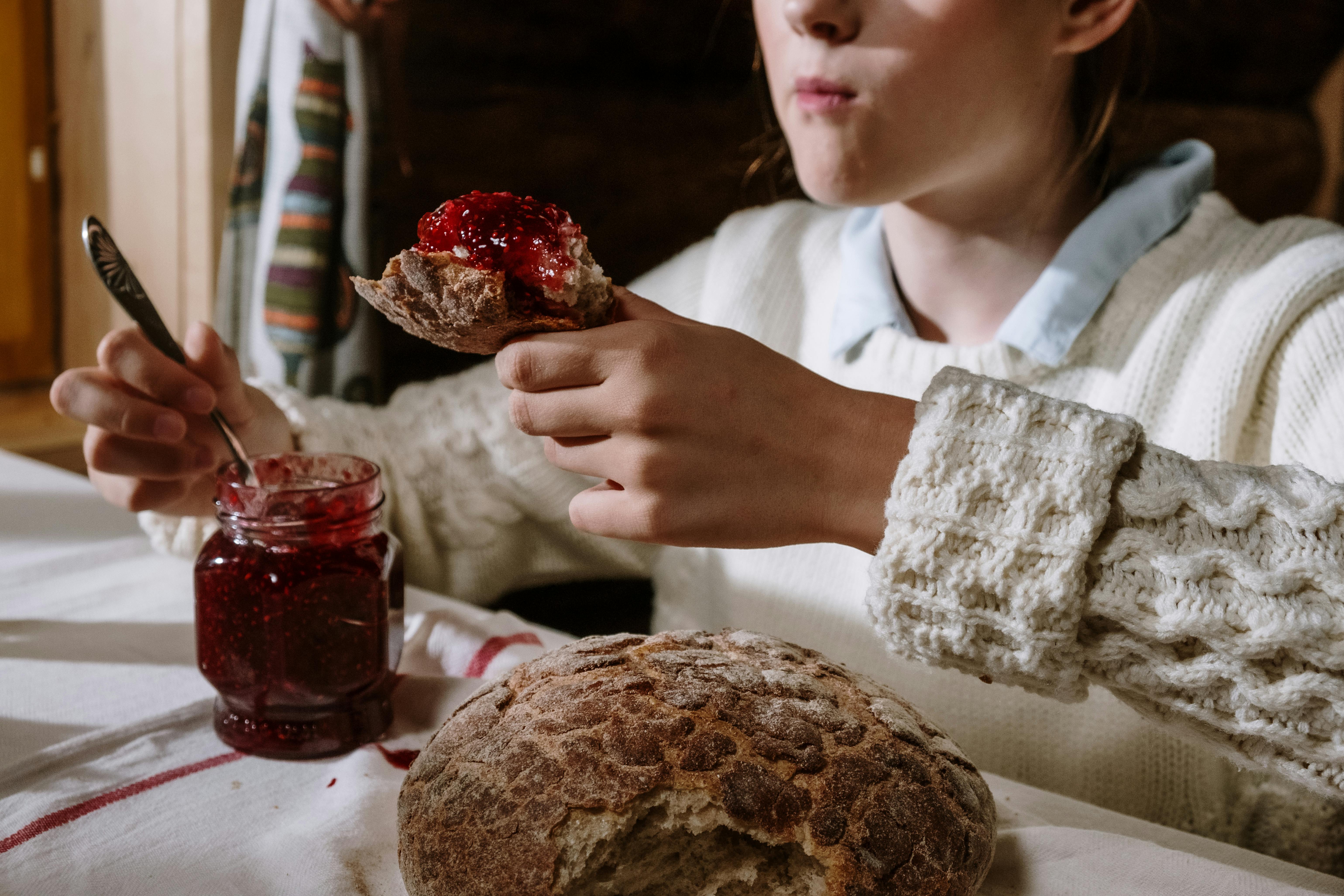 A cozy breakfast setting with fresh bread and raspberry jam being enjoyed indoors.