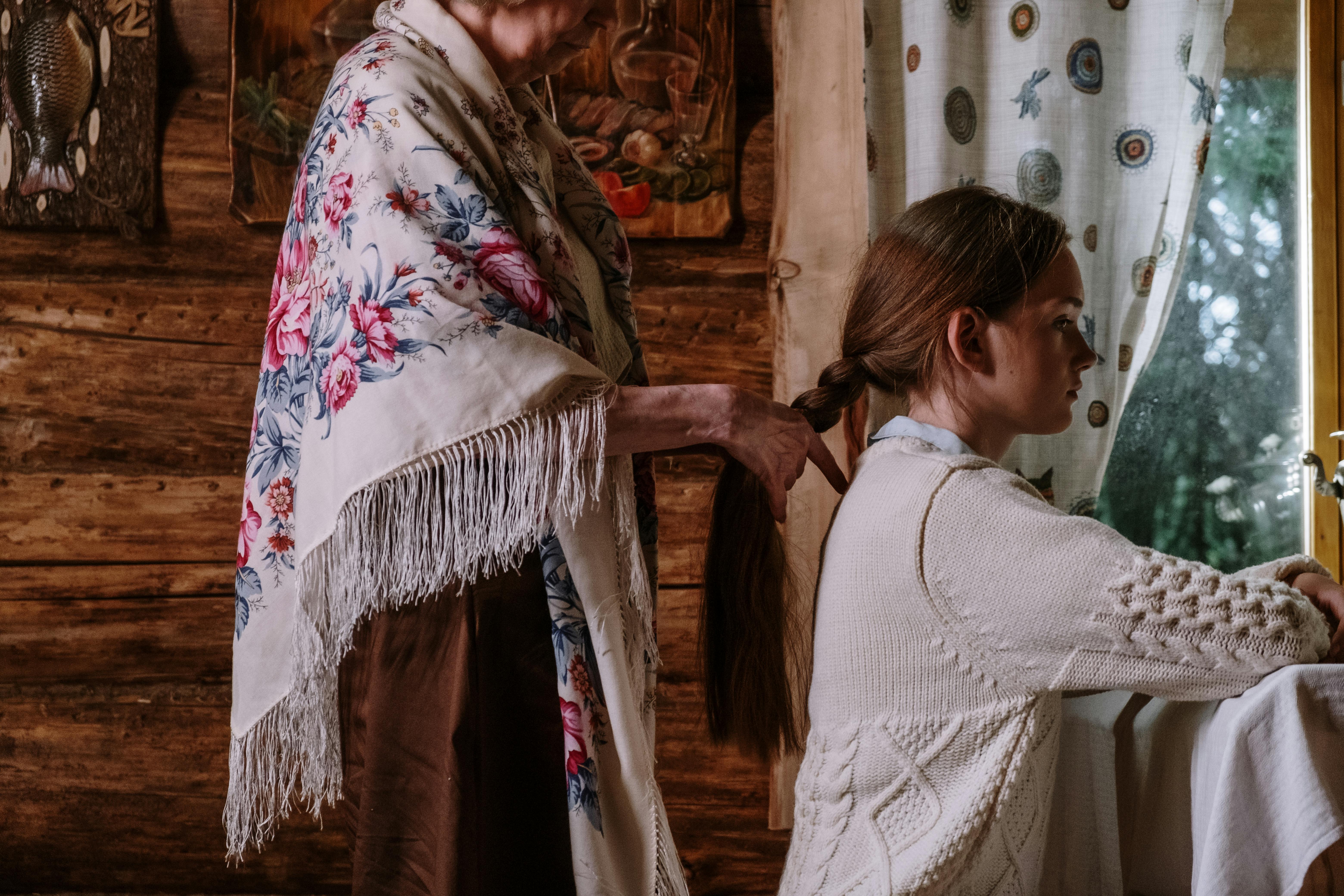 a woman braiding the girl s hair