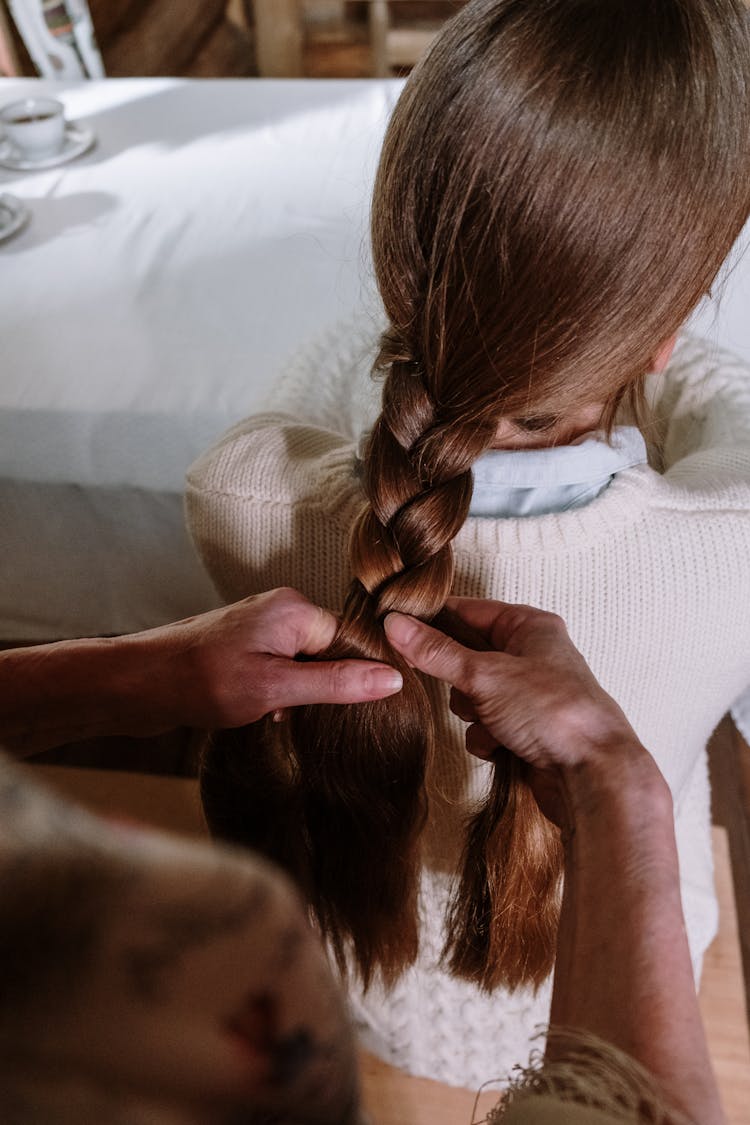 A Person Braiding A Woman's Hair 