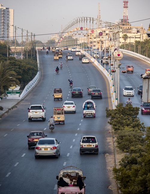 Free Modern cars and scooters driving along asphalt highway and over bridge in megapolis on cloudy day Stock Photo