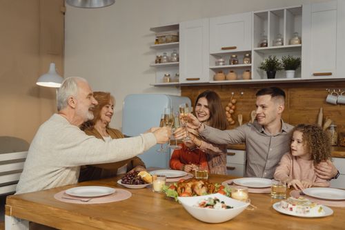 Free A joyful family toasting at a dinner table indoors, celebrating a special occasion. Stock Photo