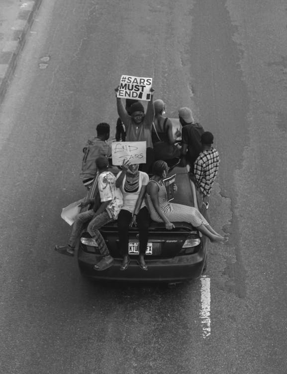 ENDSARS Grayscale Photo of 2 Men and Woman Riding on Convertible Car