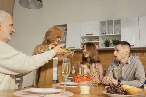 Free A multigenerational family enjoying a festive dinner indoors, sharing joy and togetherness. Stock Photo