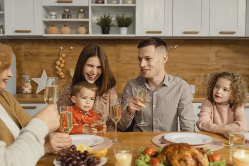 Free A joyful family celebrating together with food and champagne at a cozy dinner table. Stock Photo