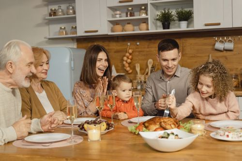 Free A joyful family gathering around a table for a Thanksgiving feast indoors. Stock Photo
