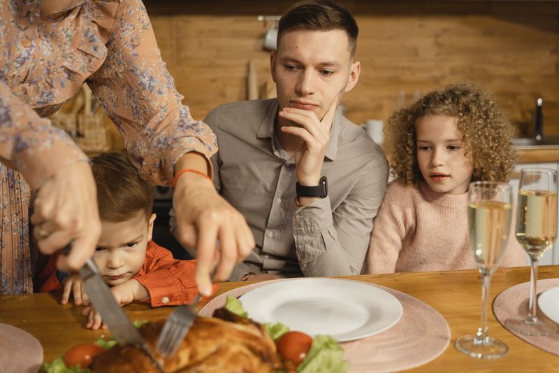 A family gathers around the table for a festive meal with roasted chicken and champagne.