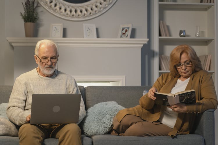 Elderly Man And Woman Sitting On Gray Sofa