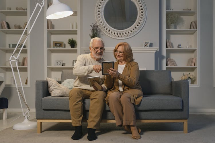 Elderly Couple Looking At Framed Photographs