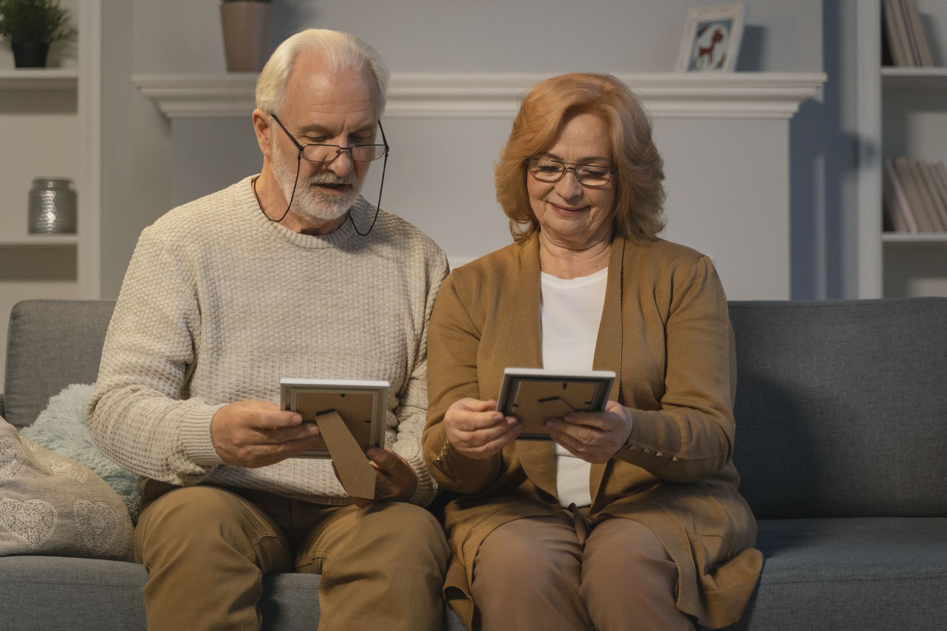 Alzheimer’s natural support — Senior couple reminiscing with photo frames in a cozy home setting.