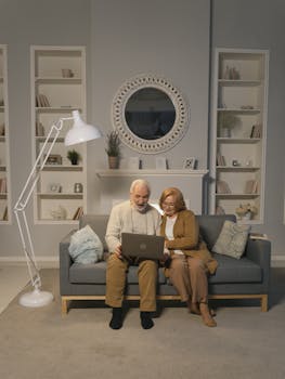 在舒适的客厅里，一对老年夫妇坐在沙发上使用笔记本电脑
