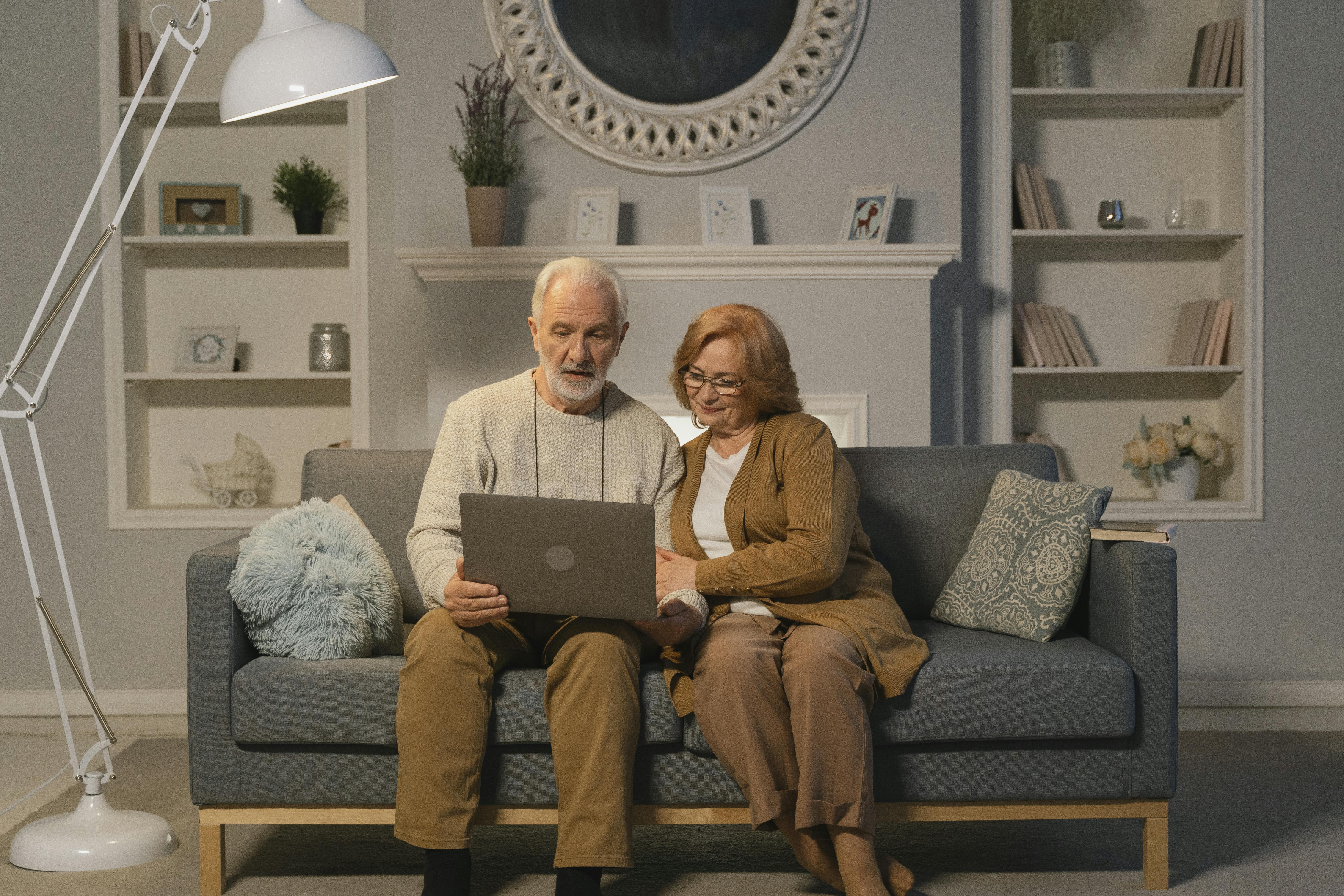 man and woman sitting on couch using macbook