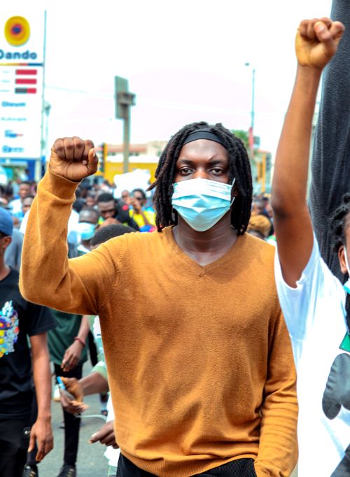 Free A group of diverse protesters wearing face masks raising fists during an outdoor protest. Stock Photo