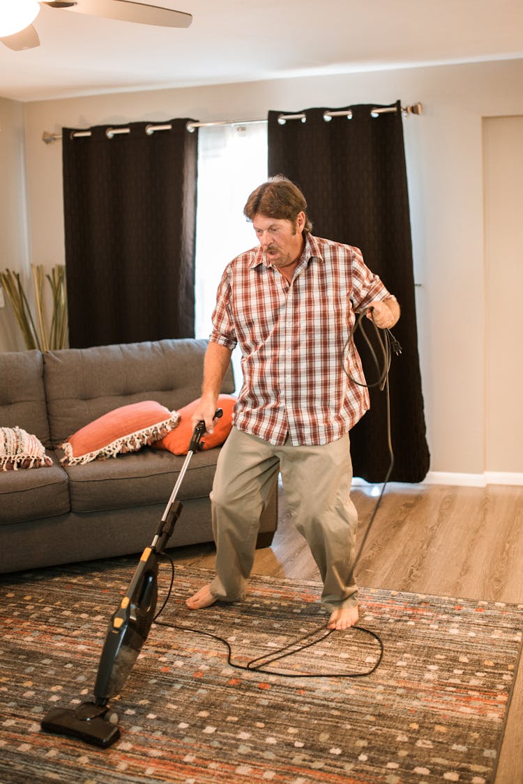 Man Cleaning The Carpet With A Vacuum